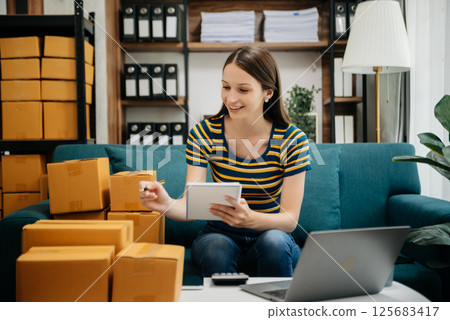 Caucasian young woman SME working using smartphone or tablet taking receive and checking online purchase shopping order to freelance online concept. Caucasian young woman SME working using smartphone or tablet taking receive and checking online purchase shopping order to freelance online concept. 125683417