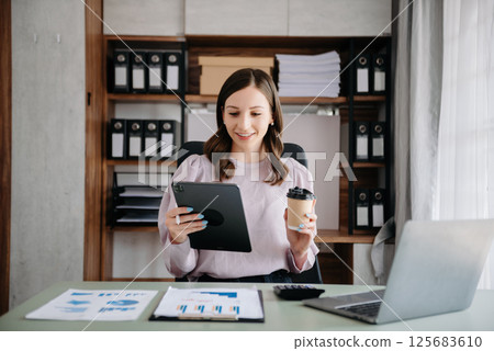 Beautiful business woman typing laptop and tablet Placed at the table at the office Beautiful business woman typing laptop and tablet Placed at the table at the office 125683610