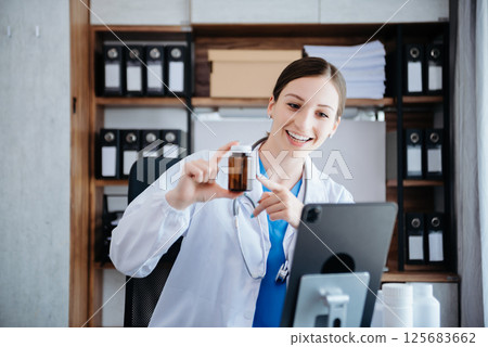 Attractive female doctor talking while explaining medical treatment to patient through a video call with laptop Attractive female doctor talking while explaining medical treatment to patient through a video call with laptop 125683662