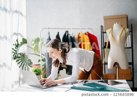 Diverse female fashion designers at work with tailor centimeters on necks and holds tablet and smartphone. 125683896