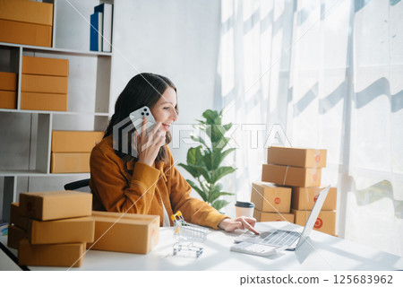 Young business owner woman prepare parcel box and standing check online orders for deliver to customer on tablet, laptop Shopping Online concept. Young business owner woman prepare parcel box and standing check online orders for deliver to customer on tablet, laptop Shopping Online concept. 125683962
