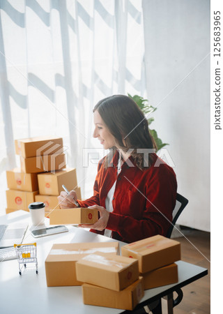 Young business owner woman prepare parcel box and standing check online orders for deliver to customer on tablet, laptop Shopping Online concept. 125683965