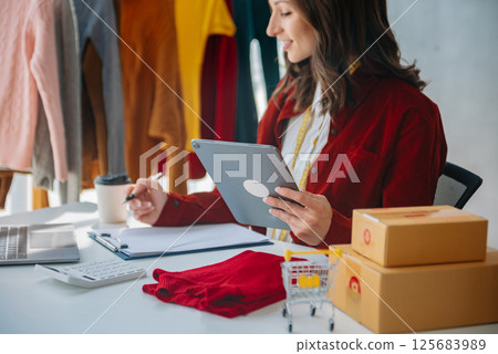 Fashion designer woman talking smart phone and using laptop with digital tablet computer in modern studio 125683989