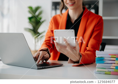 Close up of businesswoman or accountant hand typing laptop working to calculate on desk about cost at home office. Close up of businesswoman or accountant hand typing laptop working to calculate on desk about cost at home office. 125684077