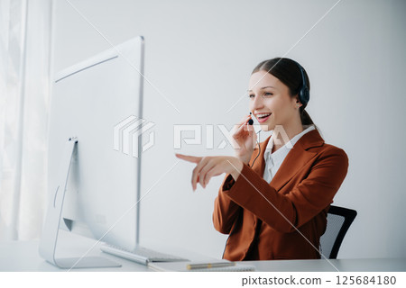 Serious call center operator in wireless headset talking with customer, woman in headphones with microphone consulting client on phone in customer support service in business center 125684180