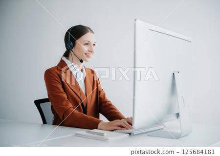 Serious call center operator in wireless headset talking with customer, woman in headphones with microphone consulting client on phone in customer support service in business center 125684181
