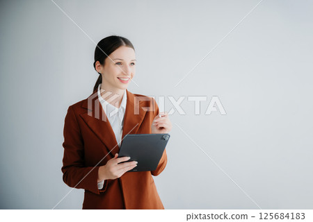 Smiling caucasian young businesswoman bank employee worker manager boss ceo looking at camera, using tablet, laptop and notepad online isolated background 125684183