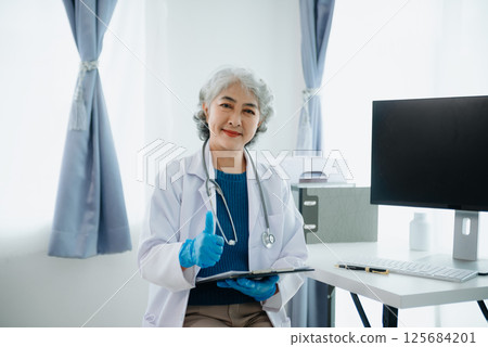Mature Asian smiling doctor or consultant sitting at a desk his neck 125684201