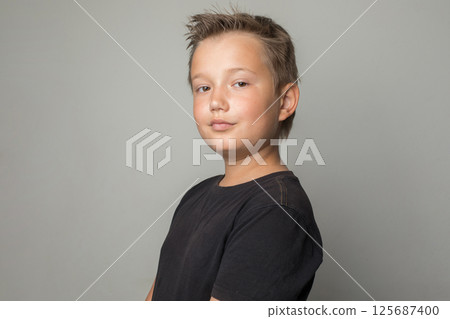 Handsome serious school age boy in black t-shirt looking at camera on white background Handsome serious school age boy in black t-shirt looking at camera on white background 125687400