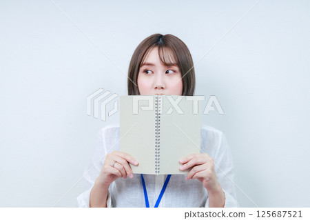 年輕女子麵朝右側,面前放著一本筆記本 年輕女子麵朝右側,面前放著一本筆記本 125687521