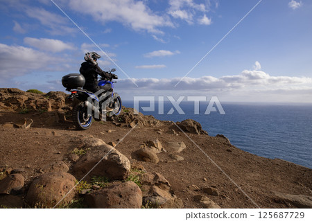 Enduro Motorcycle with Driver Posing on Sea Cliff , Madeira island 125687729