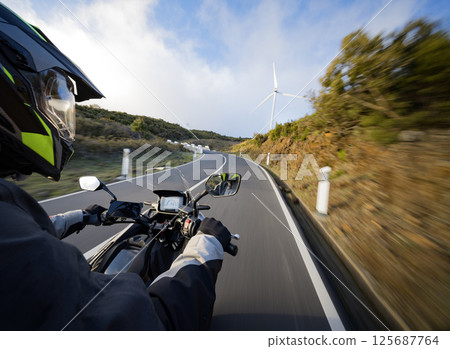 Driver riding motorcycle on empty asphalt road, handlebars view , spring mountains Driver riding motorcycle on empty asphalt road, handlebars view , spring mountains 125687764