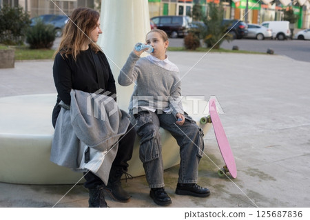 Resting family. Daughter and mother drinking water outdoors 125687836