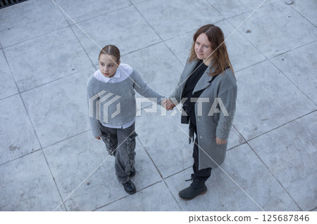 Top view of woman and young girl child walking along the streets of the city.  125687846