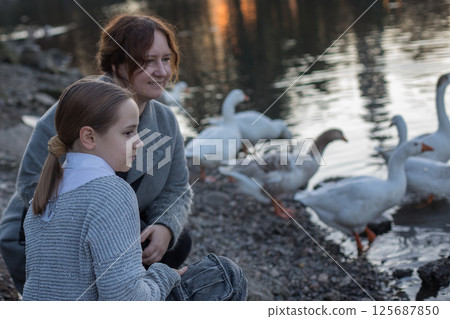 Cute woman and child with birds in park. Happy family Cute woman and child with birds in park. Happy family 125687850