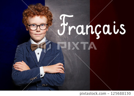 Confident child boy with crossed arms on French flag with the inscription Francais in French.  125688130