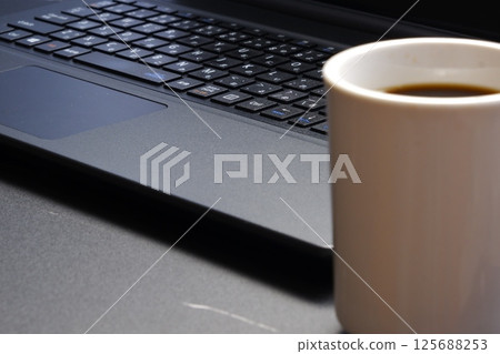Image of a man working on a laptop while drinking freshly brewed delicious coffee Image of a man working on a laptop while drinking freshly brewed delicious coffee 125688253