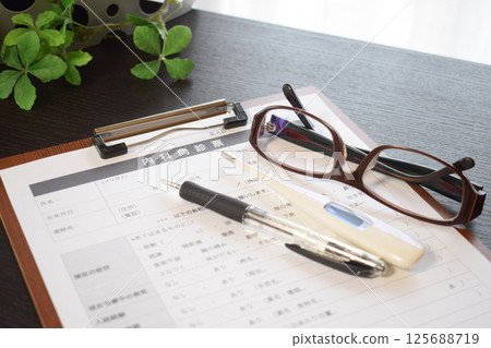 Medical questionnaire, thermometer, and reading glasses Medical questionnaire, thermometer, and reading glasses 125688719