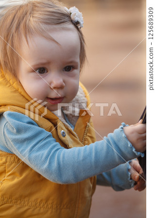 Cute baby girl 1 year old playing in the yard outdoors Cute baby girl 1 year old playing in the yard outdoors 125689309