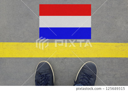 Word Start on an asphalt road with the Dutch flag and legs in shoes Word Start on an asphalt road with the Dutch flag and legs in shoes 125689315