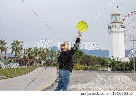Successful child young girl throwing flying disc and having fun outdoors. Happy childhood, sport  125689330