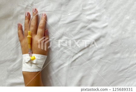 Intravenous therapy. Catheter in woman hand in hospital, medicine background 125689331