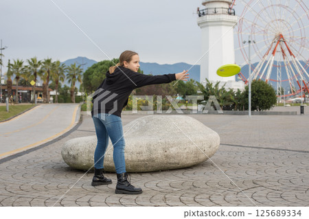 Pretty child young girl throwing flying disc and having fun outdoors. Happy childhood, sport 125689334