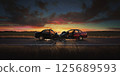 A dramatic scene showing two sedans that have collided head-on in the middle of a rural road, debris scattered across the asphalt. The crash occurred during sunset with a dramatic sky and flat open 125689593
