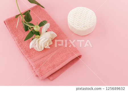 Towel with a peony flower and a sponge on the pink background. Towel with a peony flower and a sponge on the pink background. 125689632