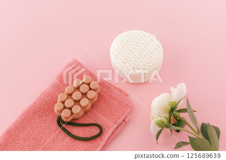 Towel with body care products and a peony flower on the pink background. Towel with body care products and a peony flower on the pink background. 125689639