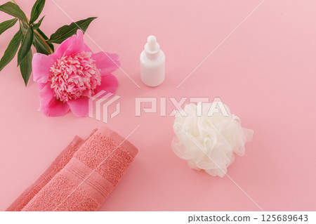 Towel with body care products and a peony flower on the pink background. Towel with body care products and a peony flower on the pink background. 125689643
