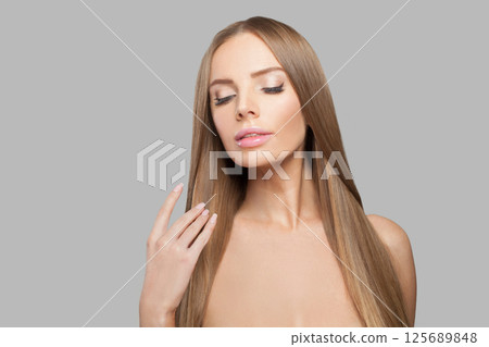 Gorgeous woman face. Model with long brown hair and make-up on grey background. 125689848