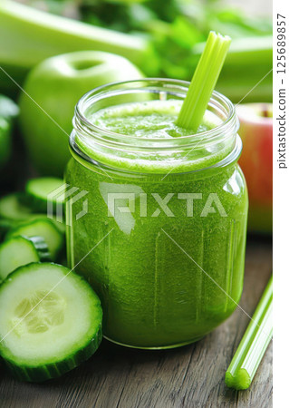 Fresh green detox smoothie with celery, cucumber, and green apple in a mason jar on wooden table, captured in vibrant close-up with healthy raw ingredients. 125689857