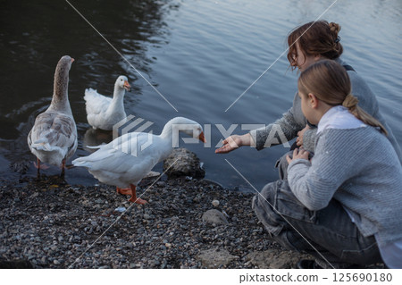 Lifestyle portrait of woman and child with birds in park. Happy family 125690180