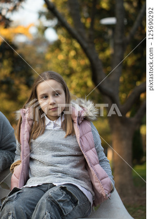 Attractive little girl in pink gilet outdoors portrait 125690292