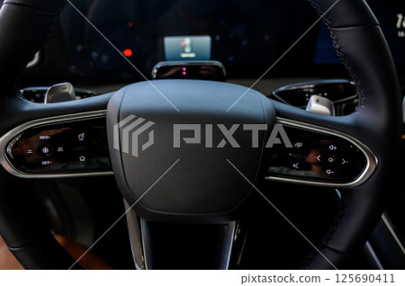 A close-up of a modern car's steering wheel with control buttons 125690411