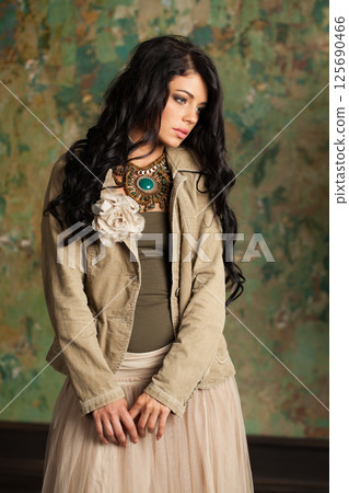 Pretty young fashion woman standing against green stucco wall background Pretty young fashion woman standing against green stucco wall background 125690466