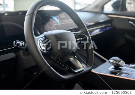 Modern car interior with black steering wheel, digital instrument panel Modern car interior with black steering wheel, digital instrument panel 125690501