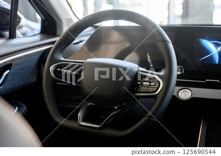 Modern car interior with black steering wheel, digital instrument panel 125690544