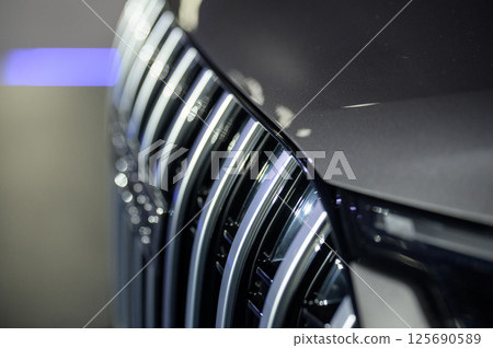 Close-up of the facade of a new car in a car showroom. The radiator grille of a car Close-up of the facade of a new car in a car showroom. The radiator grille of a car 125690589