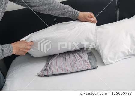 puts his pajamas under his pillow on his bed puts his pajamas under his pillow on his bed 125690788