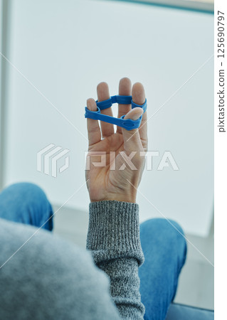 man uses an elastic band to exercise his fingers man uses an elastic band to exercise his fingers 125690797