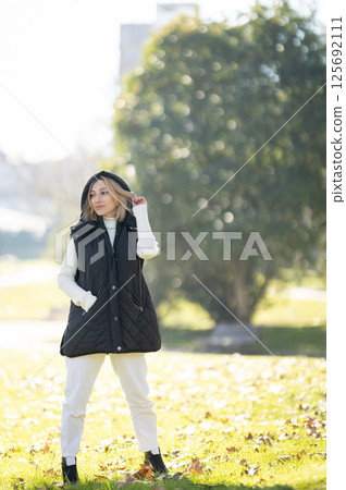 Fashion model posing in a park during a sunny autumn day 125692111