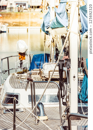 Sailboat docked in marina with detailed view of deck and rigging, background Sailboat docked in marina with detailed view of deck and rigging, background 125692320