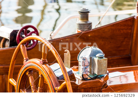 Sailboat helm with wooden wheel and nautical equipment in sunlight, background Sailboat helm with wooden wheel and nautical equipment in sunlight, background 125692329