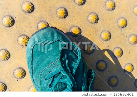 Green shoe on tactile paving for pedestrian safety 125692401
