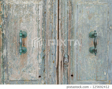 Weathered double wooden door with vintage handles 125692412