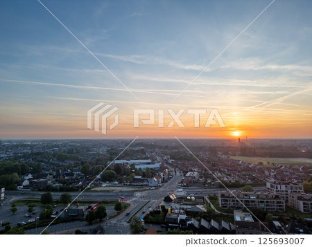 Experience a breathtaking sunset illuminating a tranquil townscape under a beautifully cloudy sky 125693007