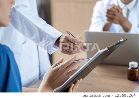 Doctor reviewing medication instructions with a patient in detail 125693264
