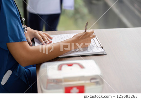 Healthcare professional taking notes while reviewing patient data 125693265